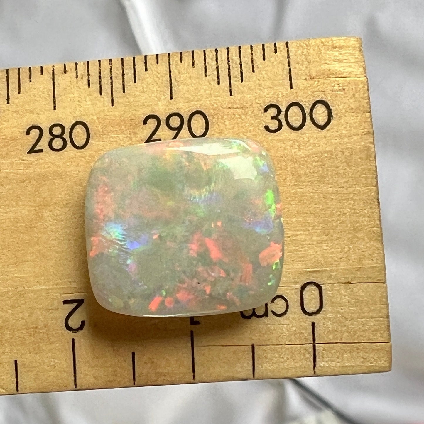 Stunning cushion cut semi black opal from Grawin, near Lightning Ridge, displaying an impressive play of colour including plenty of reds.