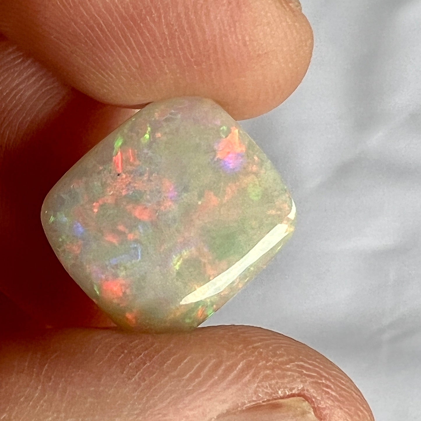 Stunning cushion cut semi black opal from Grawin, near Lightning Ridge, displaying an impressive play of colour including plenty of reds.