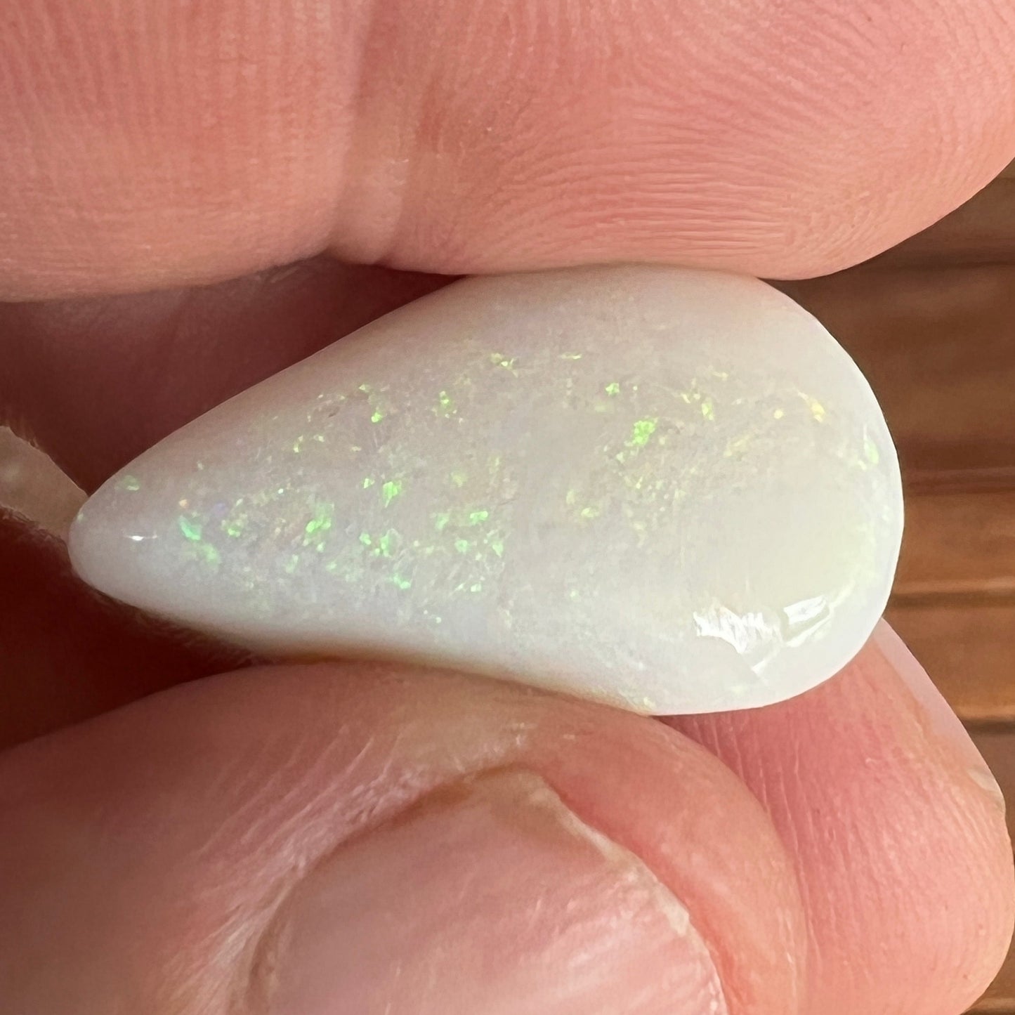 Large teardrop shaped solid white opal from Coober Pedy, featuring striking pinfire greens. Ready for a pendant. An excellent bargain.