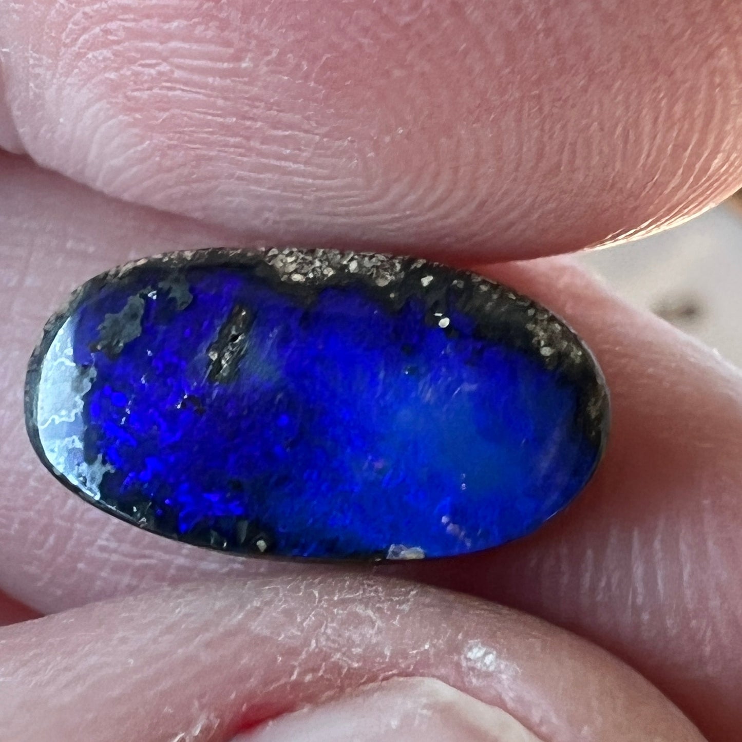 A great shaped little boulder opal with bright blues.